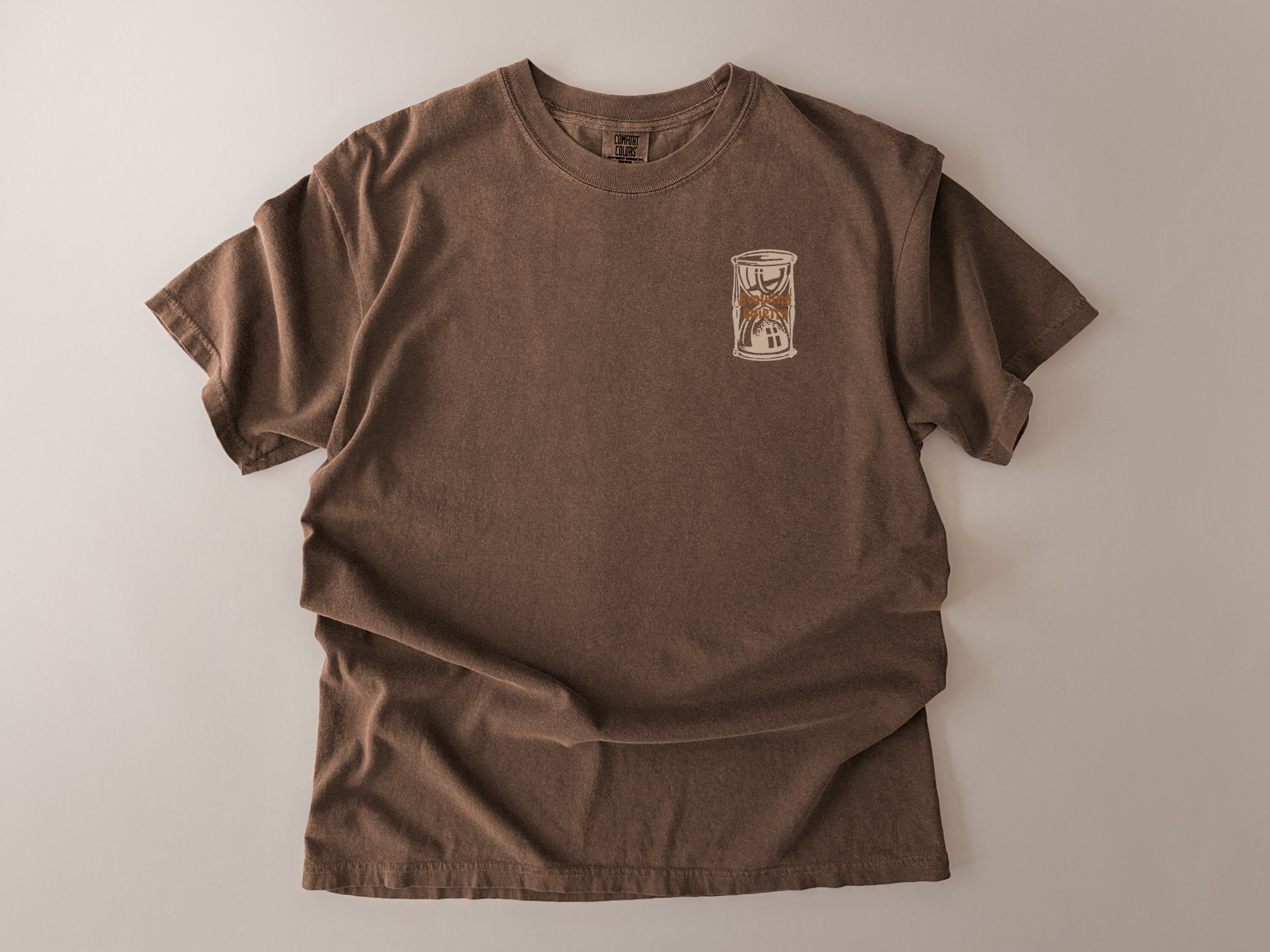 Brown t-shirt with a small graphic on a light beige background