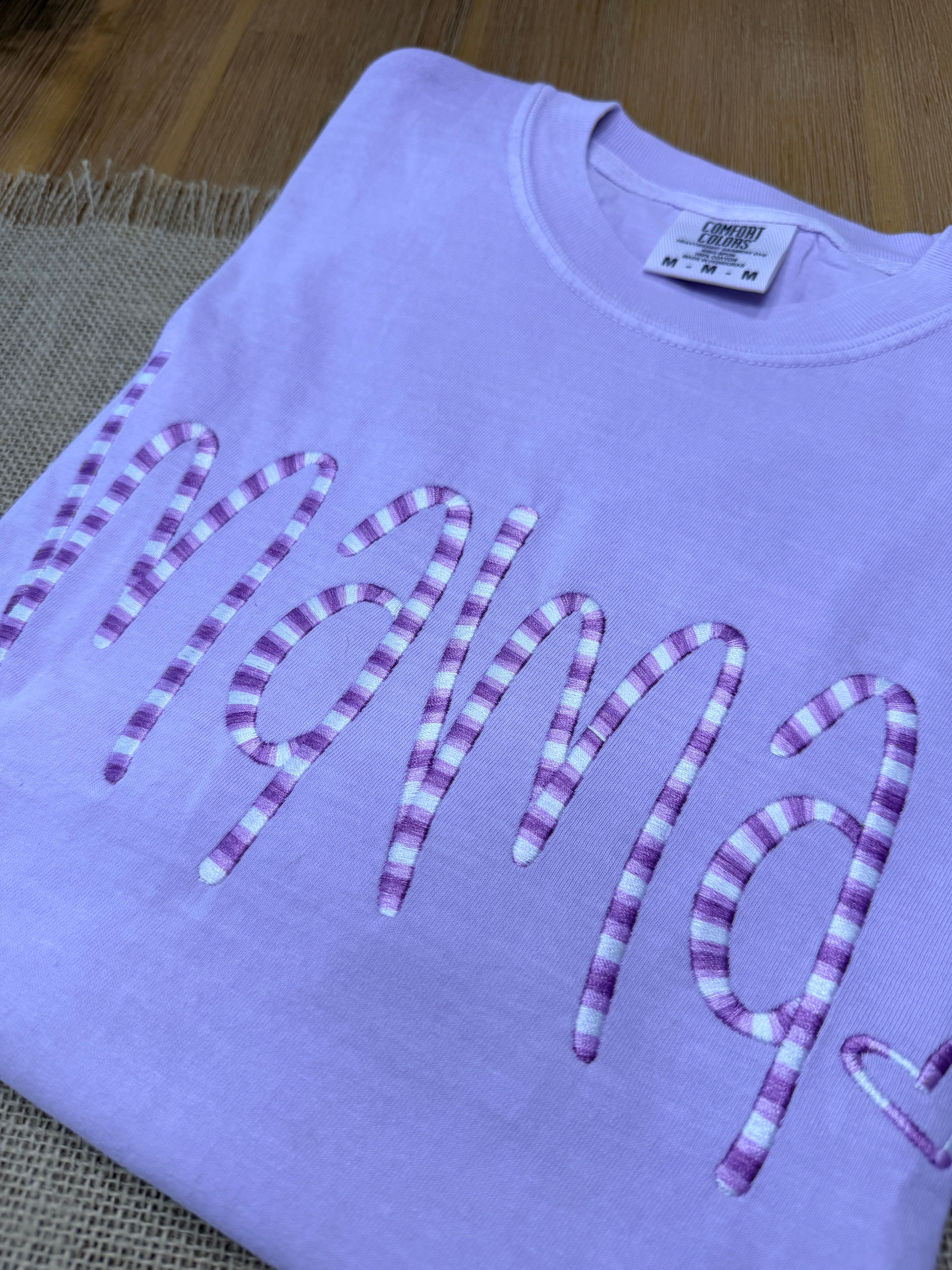 Purple t-shirt with decorative text on a wooden surface