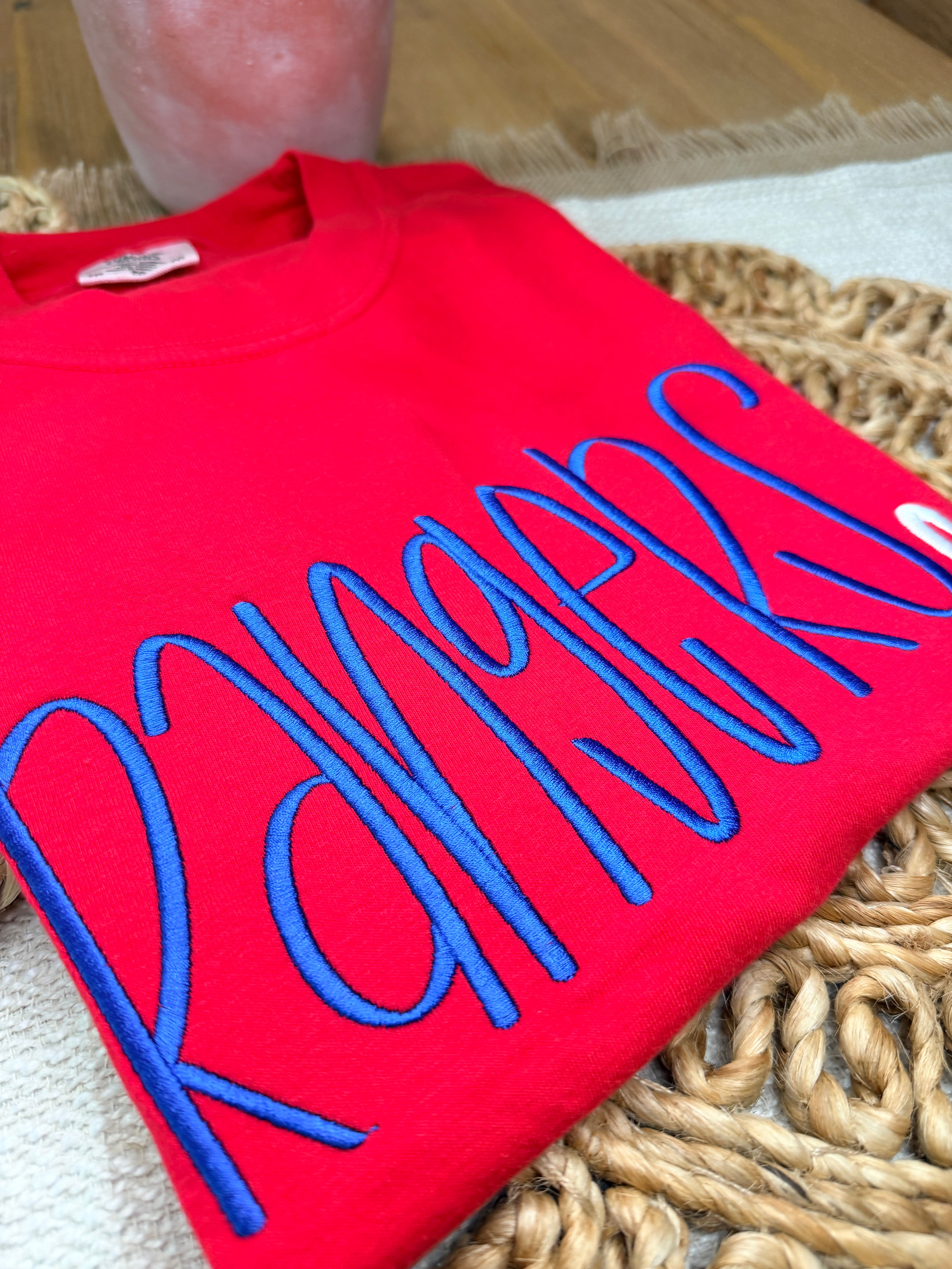 Red Comfort Colors tee with large blue “Rangers” script embroidery and small white heart detail. Soft garment-dyed cotton with relaxed unisex fit and bold front design.