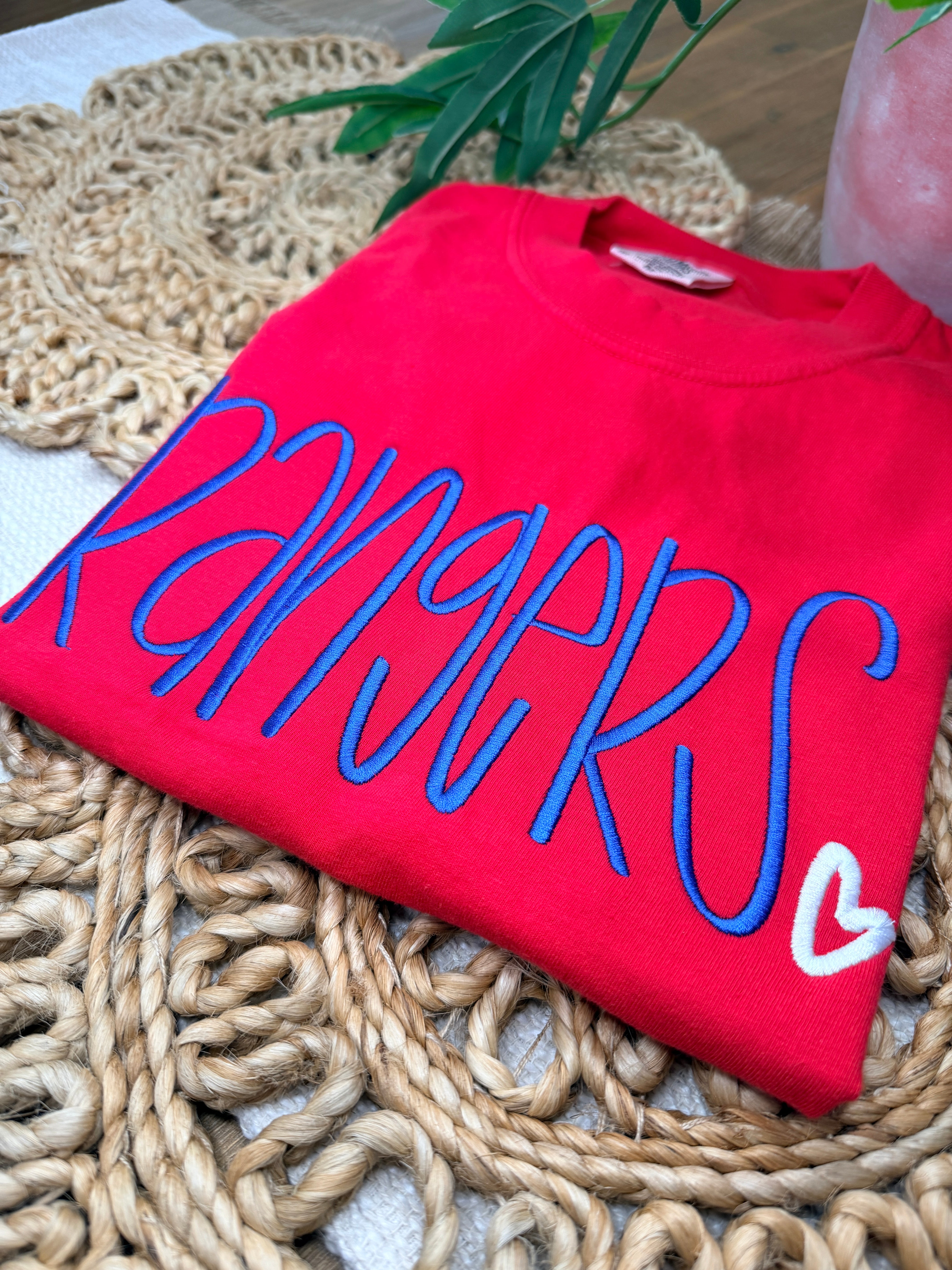 Red Comfort Colors tee with large blue “Rangers” script embroidery and small white heart detail. Soft garment-dyed cotton with relaxed unisex fit and bold front design.