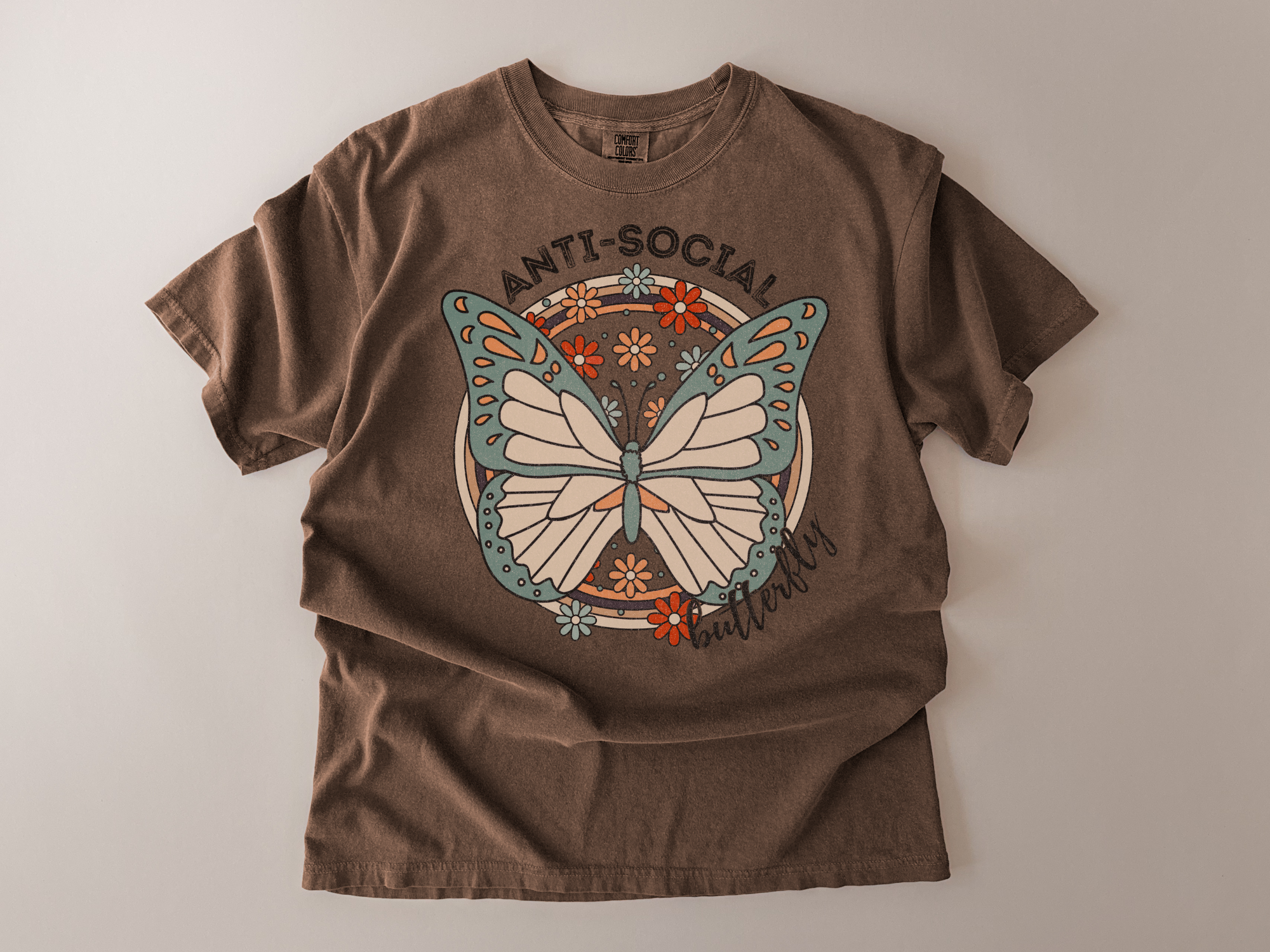 Brown t-shirt with a butterfly graphic and 'ANTI-SOCIAL' text on a beige background