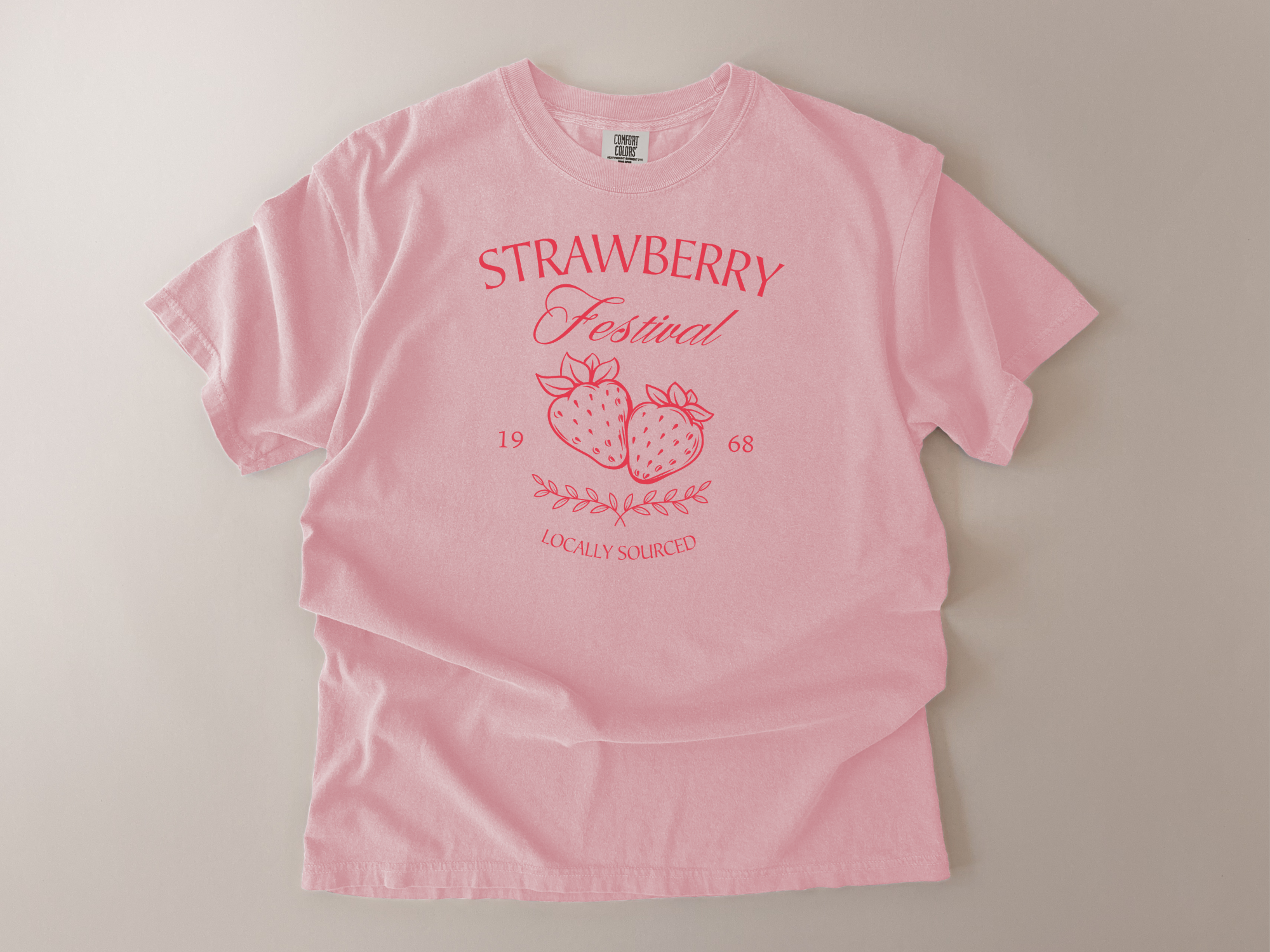 Pink t-shirt with 'Strawberry Festival' design on a beige background