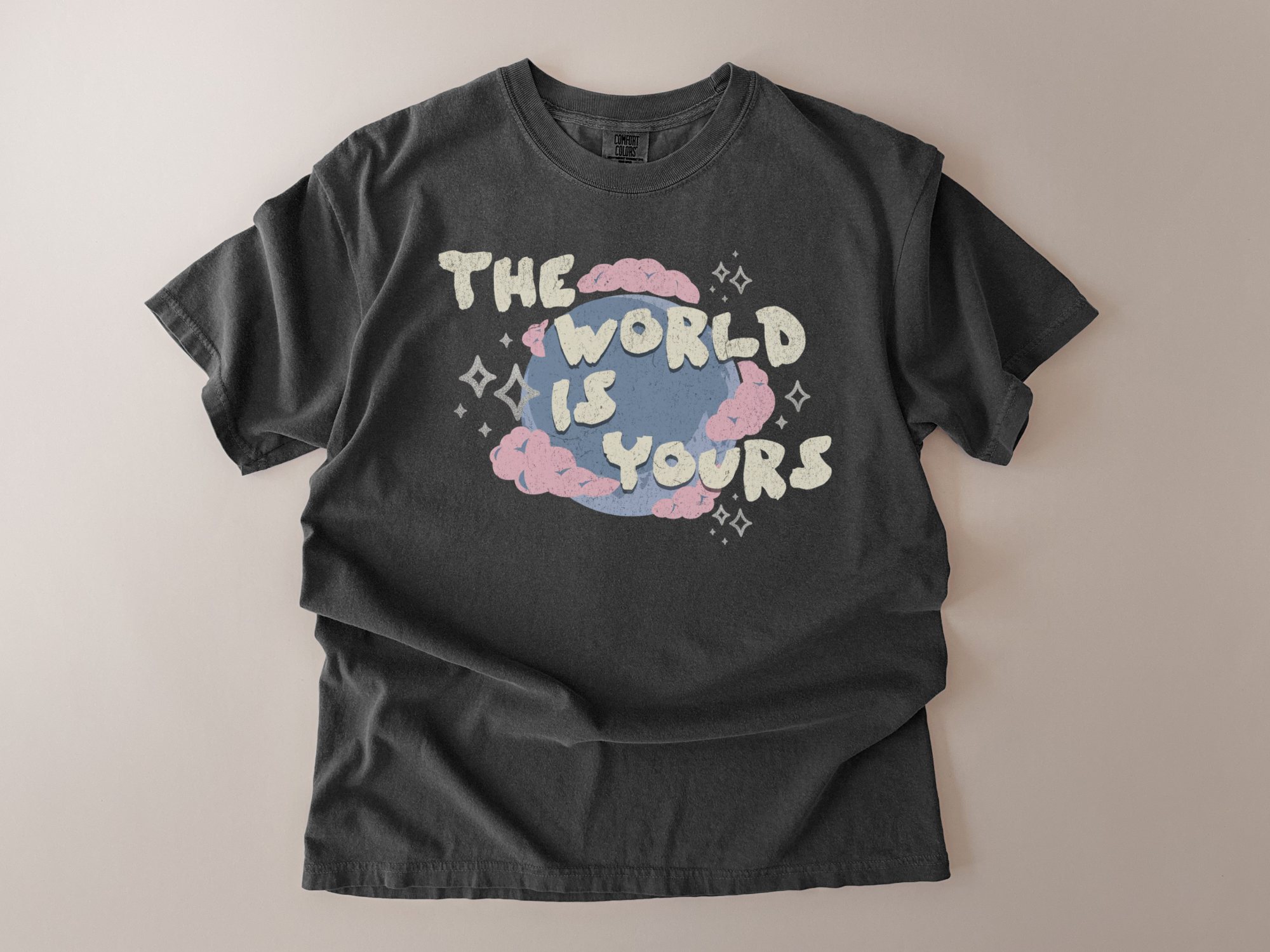 Black t-shirt with 'The World is Yours' graphic design on a beige background
