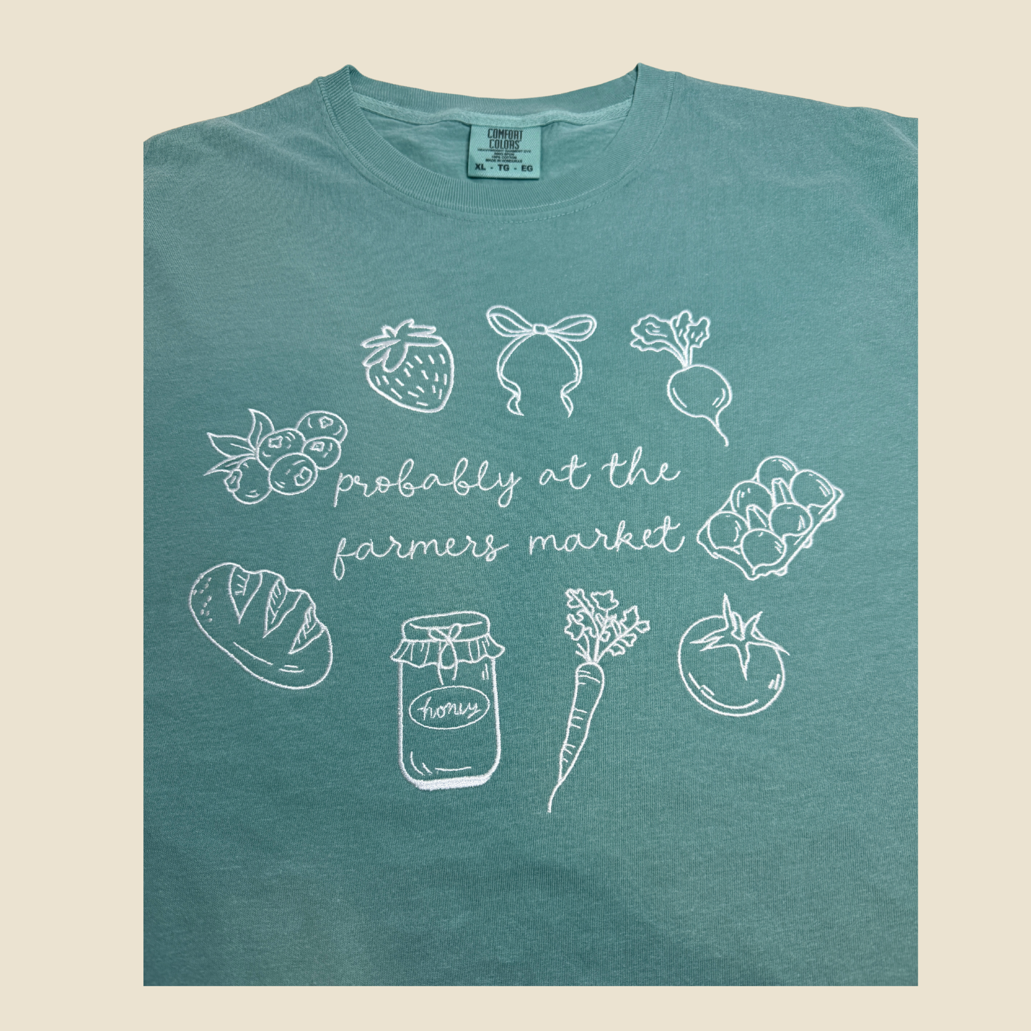 Teal t-shirt with white illustrations and text on a beige background