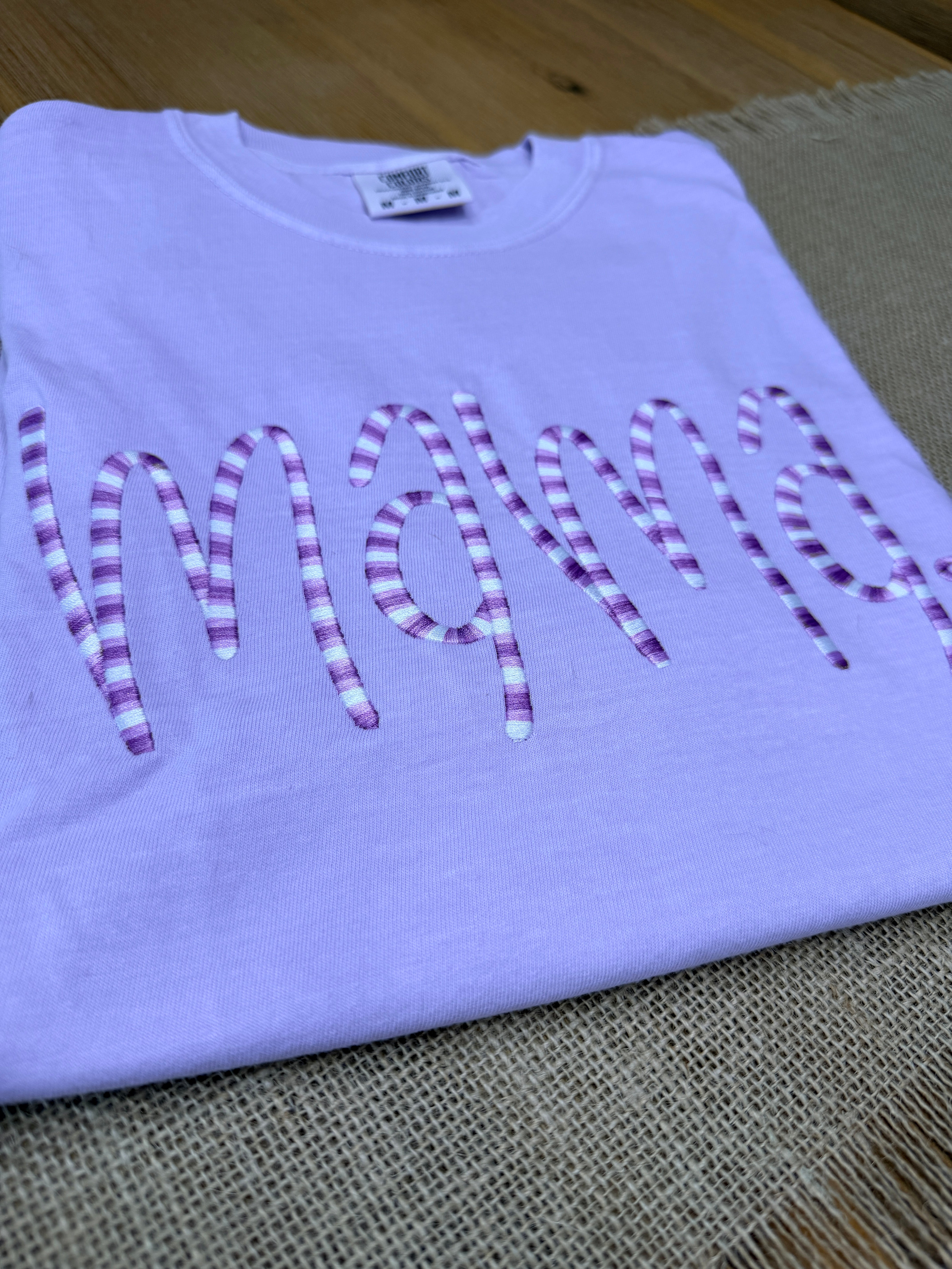 Light purple shirt with pink text on a wooden floor