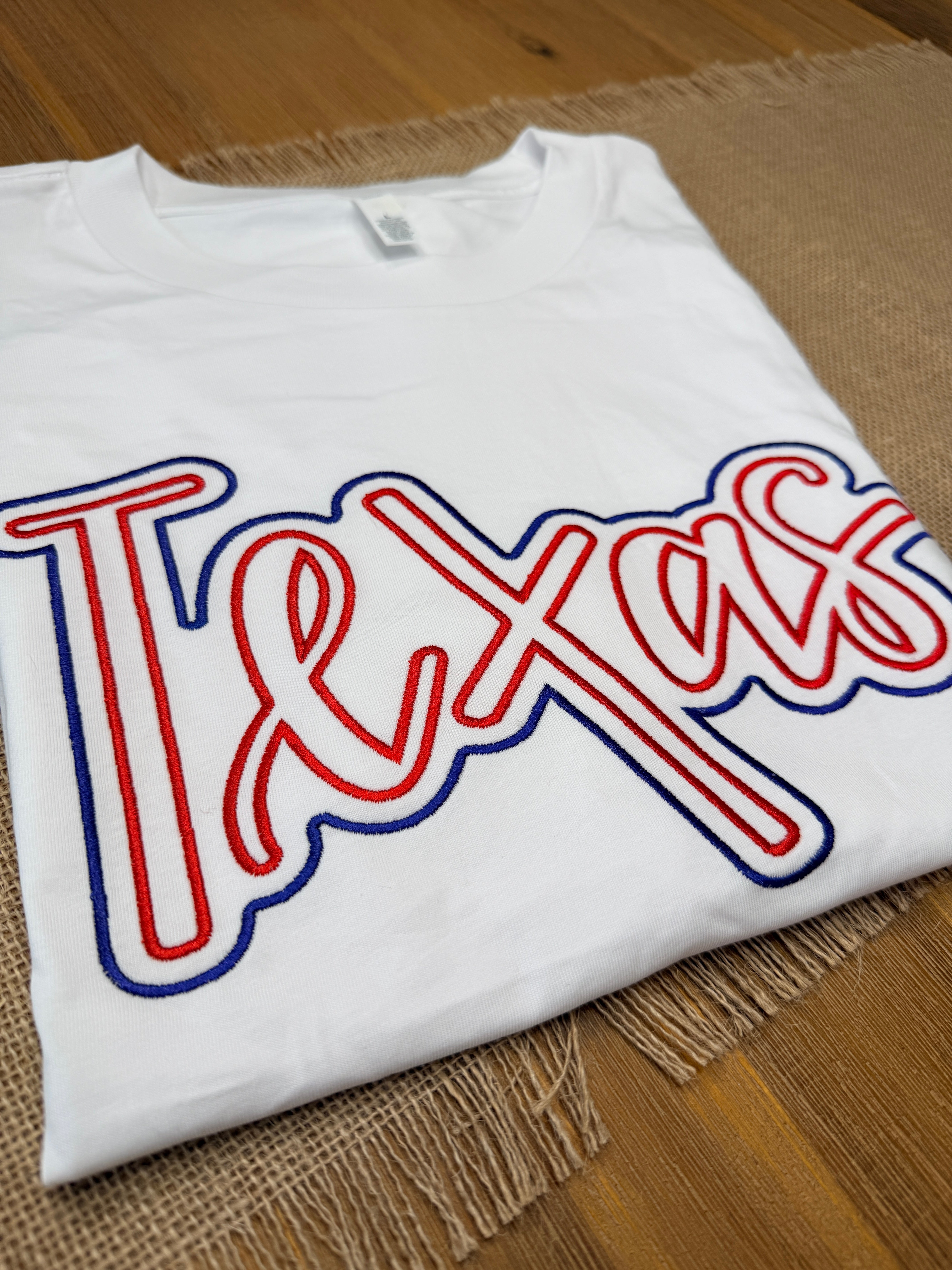 White t-shirt with red and blue graphic design on a wooden surface