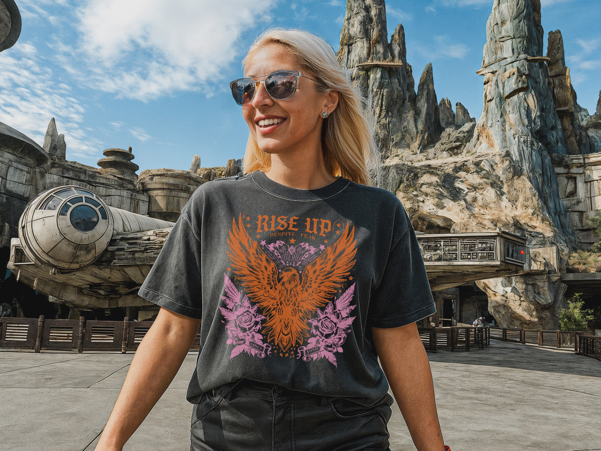 Woman wearing a t-shirt with an eagle design and 'Rise Up' text, standing in front of a themed landscape.