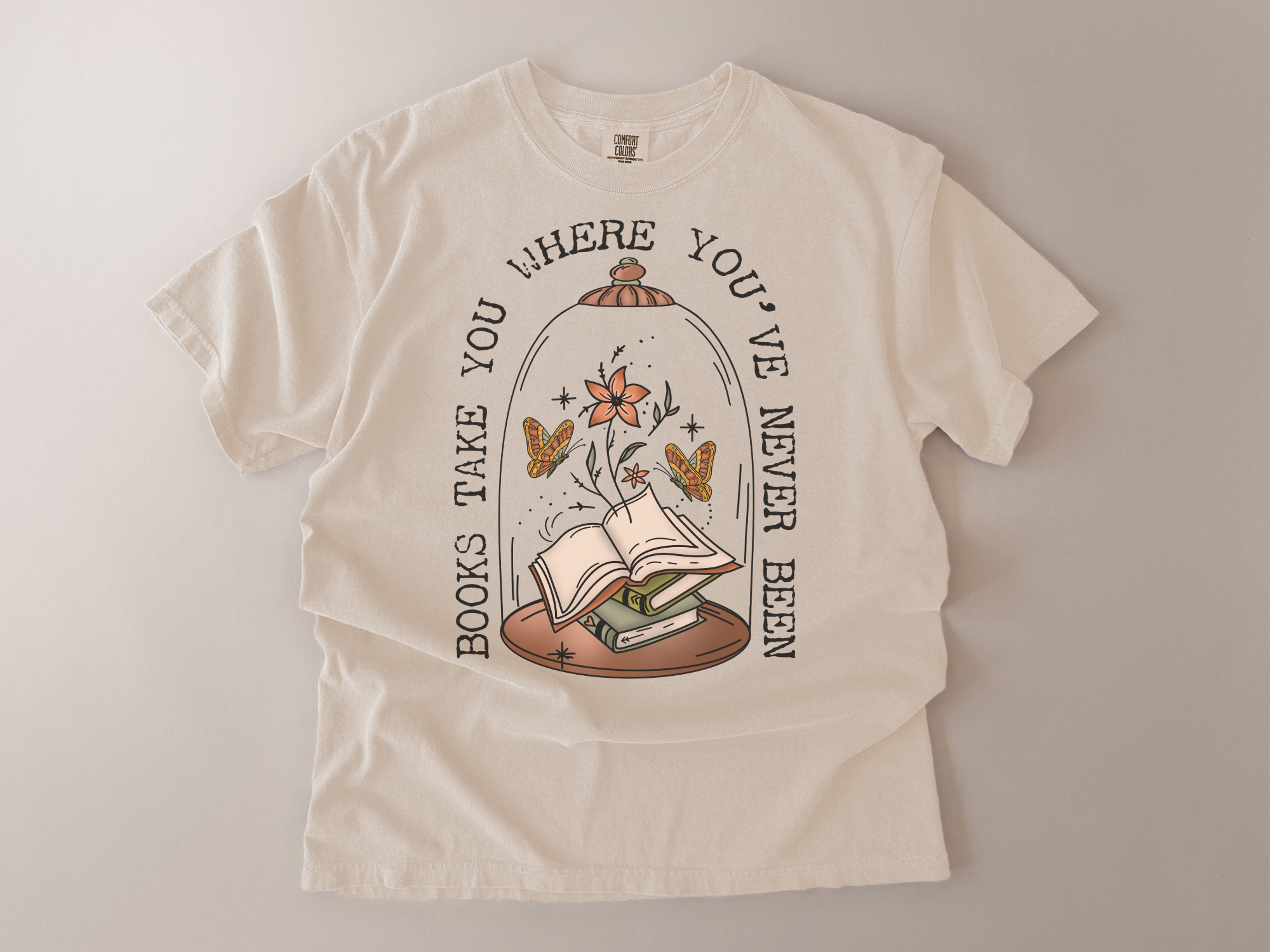 Beige t-shirt with a graphic design of books and flowers under a glass dome on a plain background